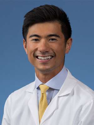 Dr. Kekoa Taparra posing, wearing a white coat and smiling.