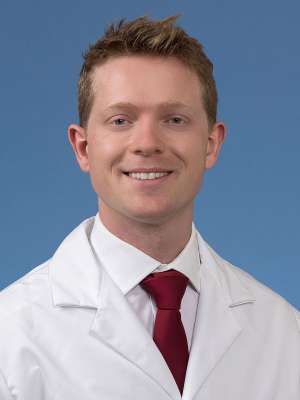 Dr. Sebastian Green in a white coat and tie smiling 