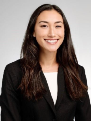 Professional headshot of a woman with long, dark hair, wearing a black blazer.