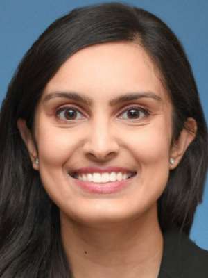 Smiling woman headshot against blue background.