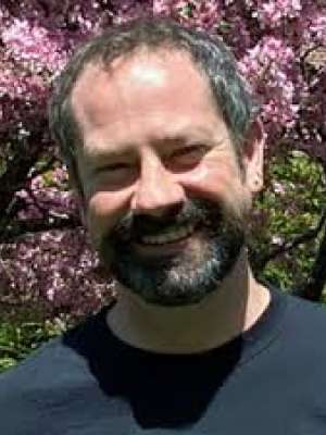Smiling bearded man standing in front of a pink flowering tree