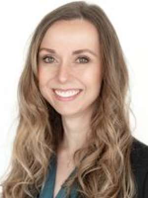 Smiling woman in blazer with long wavy hair on a white background