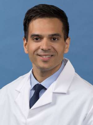 White coat head shot of Christopher Hernandez, smiling at the camera