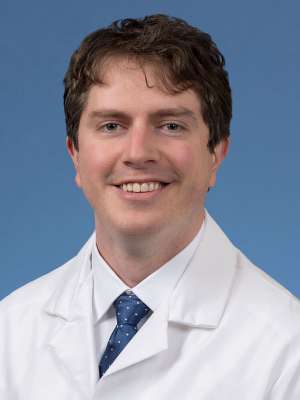 Head shot of Dylan Calame in a white coat, looking at camera