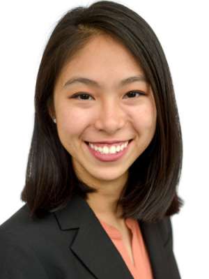 Professional headshot of person in dark blazer and peach blouse with face obscured