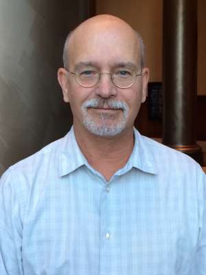 Bald man in light blue shirt indoors