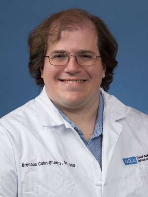 Head shot of Brendan Cohn-Sheehy in white lab coat, smiling at camera