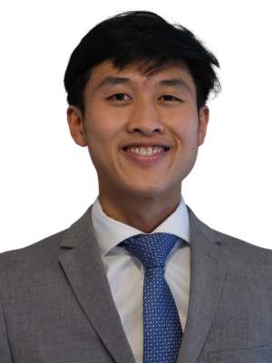 Headshot of a man in gray suit and blue tie smiling
