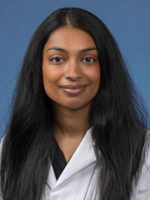 Head shot of Mahima Sukumar in white lab coat, smiling at camera