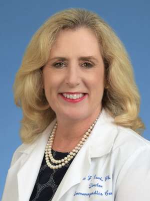 Elaine Reed, PhD, in a white lab coat
