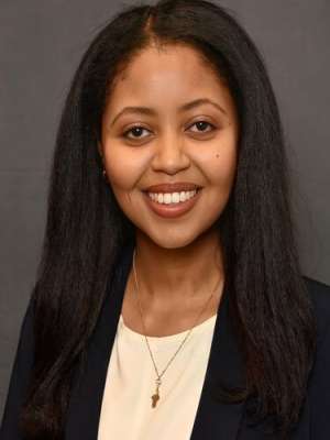 Headshot of Enat wearing a black suit and cream shirt
