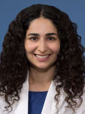Head shot of Nicki Karimi-Mostowfi, MD in white coat, smiling at the camera