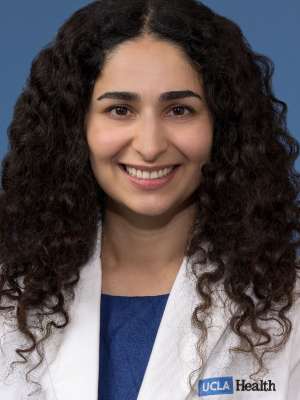 Head shot of Nicki Karimi-Mostowfi, MD in white coat, smiling at the camera