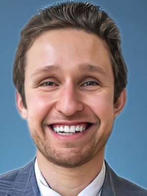 Smiling man in suit jacket and shirt against blue background.