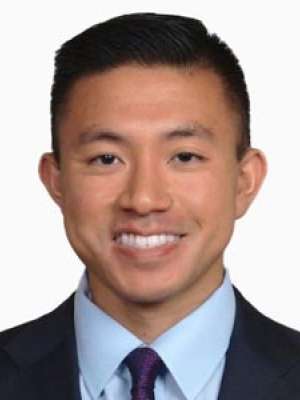 Smiling man headshot wearing suit and tie on white background