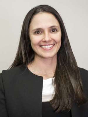 Professional headshot of smiling woman with long dark hair wearing black blazer