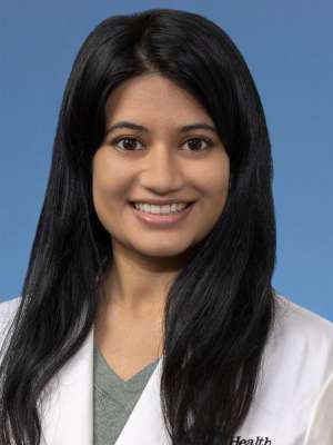 Head shot of Priyanka Deshpande, in white coat, smiling at camera