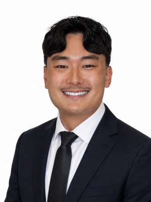 Man in dark suit and tie smiling against white background