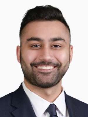 Basil Hashimi smiling headshot in suit and tie against white background.