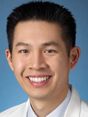 Smiling person wearing a white coat against a blue background