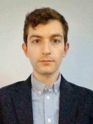 Head-and-shoulders portrait of a man wearing a navy blazer and light blue collared shirt.