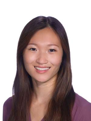 Smiling woman headshot, long dark hair, purple top, white background