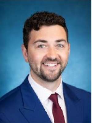 Smiling man in navy suit and burgundy tie on blue background