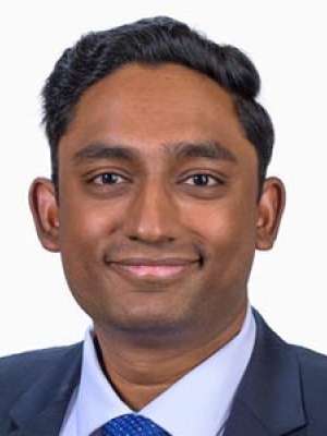Surendra Likith, headshot smiling in suit and tie.