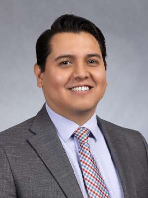 Smiling man in gray suit and striped tie headshot