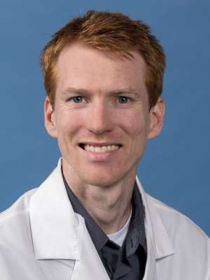 Luke Helminiak, PhD in a white lab coat