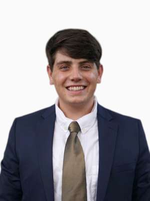 Headshot of a smiling young man in a navy suit and gray tie.