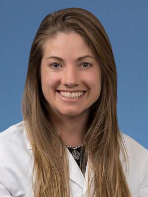 Head shot of Neva Lundy in a white coat, smiling at camera