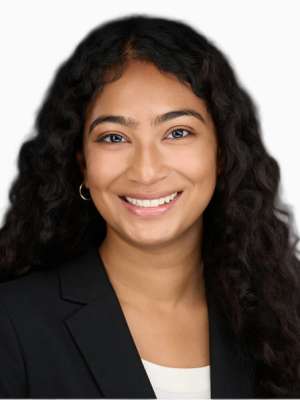 Smiling woman with long curly hair in black blazer and white top on white background.