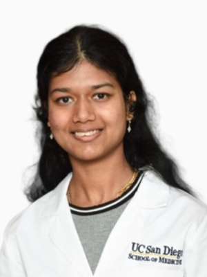 Smiling woman in white medical coat headshot.