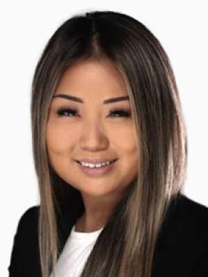 Smiling headshot of a person wearing a black blazer and white top