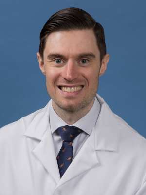 Head shot of John Thompson in white lab coat, smiling at camera