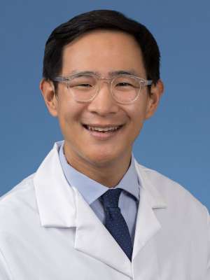 Head shot of Jerry Shen in a white coat, smiling at camera
