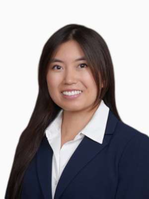 Professional headshot of a woman smiling in a navy blazer and white blouse on white background