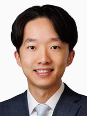 Sheng Qicong headshot smiling in suit and tie