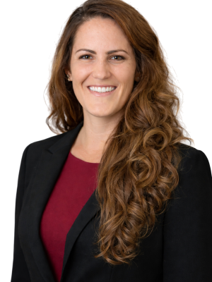Krista dollar: Smiling woman with long curly hair wearing a black blazer and burgundy top.