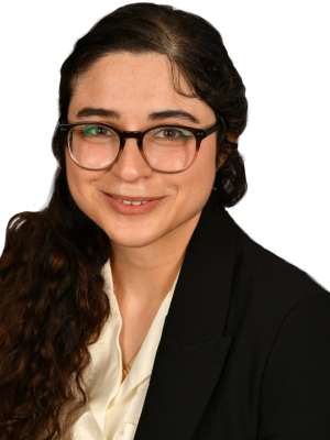 Person with glasses and dark hair smiling in professional headshot