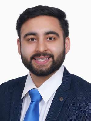 Smiling man in navy suit and blue tie headshot on white background.