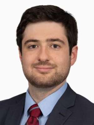 Person headshot wearing suit and tie against white background