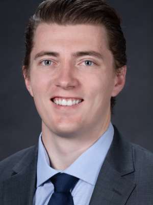 Headshot of Jake Stenzel, a young man with dark hair, a clean-shaven face, and a warm, inviting smile.