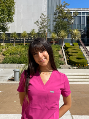 Tiana, who has brown hair and bangs, wearing pink scrubs