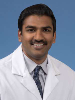 Head shot of Rohan Rao in a white coat, smiling at camera