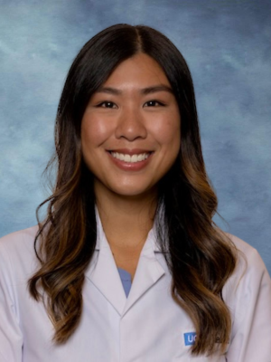 A headshot of Dr. Nicole Nguyen with long brown hair, smiling and wearing a white lab coat. 