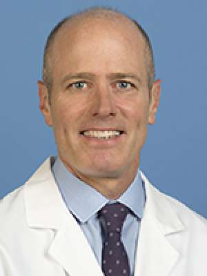 Head shot of Stanley Carmichael Jr wearing a white lab coat, smiling at the camera