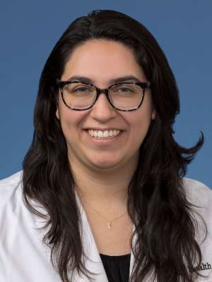 Head shot of Brenda Gutierrez, MD, PhD in a white coat, smiling at the camera