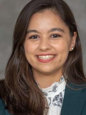 Smiling woman wearing green blazer and white patterned blouse